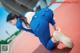 A woman in a blue uniform crouching down on a track.