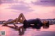 A woman laying on the edge of a swimming pool at sunset.