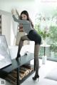 A woman in black stockings and high heels posing on a table.