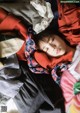 A woman laying on top of a pile of clothes.