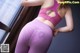 A woman in a pink sports bra top and purple leggings.