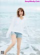 A woman standing on a beach next to the ocean.